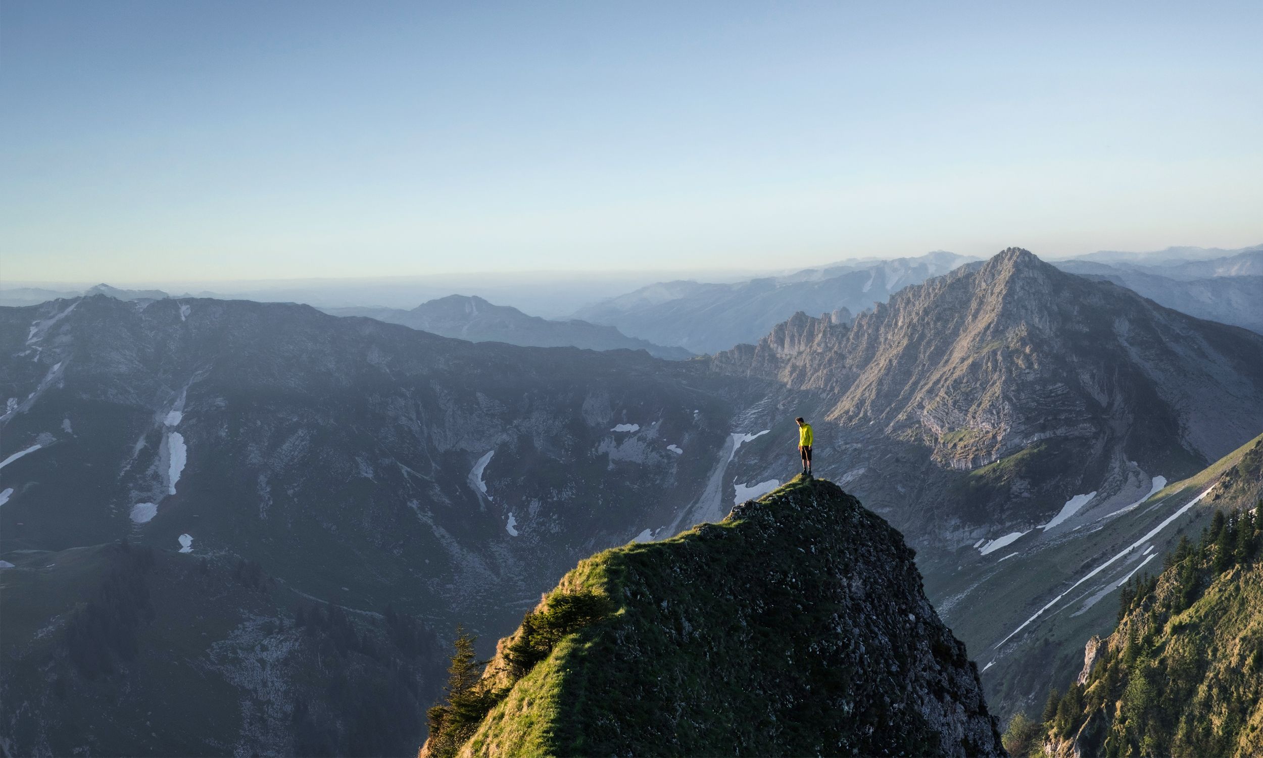Bergsteiger auf Gipfelgrat blickt über Alpenpanorama – Symbolbild für Veränderung und Erfolg