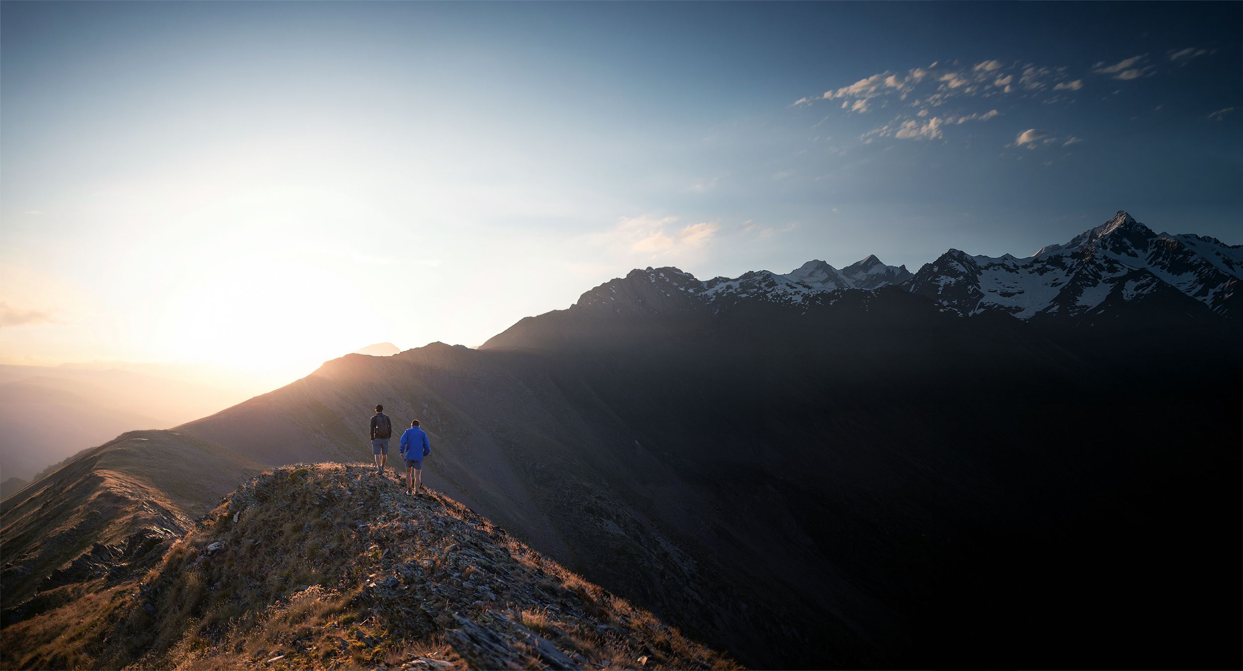 Zwei Bergsteiger auf Gratwanderung im Sonnenaufgang – Symbolbild für gemeinsamen Veränderungsprozess